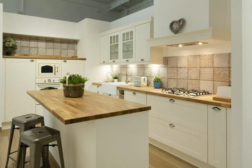 Moderní bílá kuchyně s odtrůvkem a dřevěnou pracovní deskou